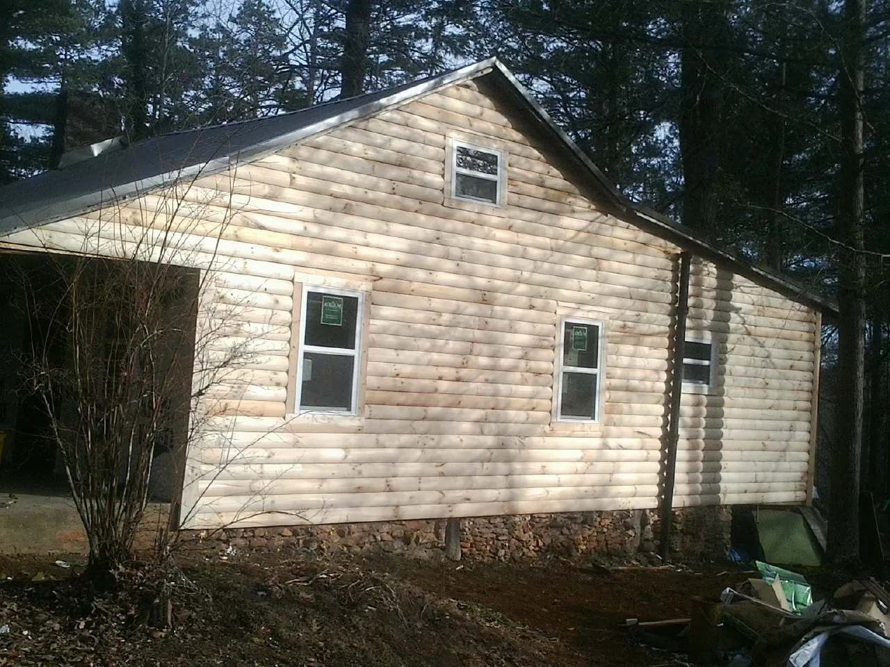 New log siding and dark metal roofing on a gable end in Spirit Lake