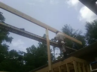 Carpenter setting a ridge beam over a new addition frame — Ice Dam Removal by Roofing Brothers in Spirit Lake