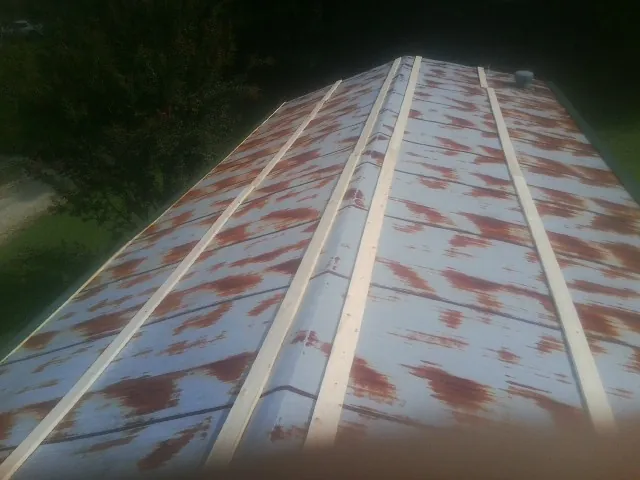 Rusted metal roof panels with new wood purlins before replacement — Storm Damage Roof Repair in Spirit Lake by Roofing Brothers