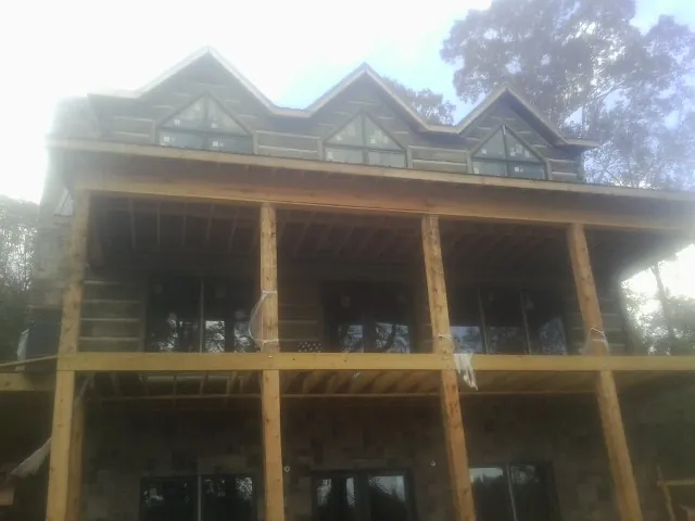 Dormers and porch framing on a large log home under construction — Roof Coating work by our crew in Spirit Lake