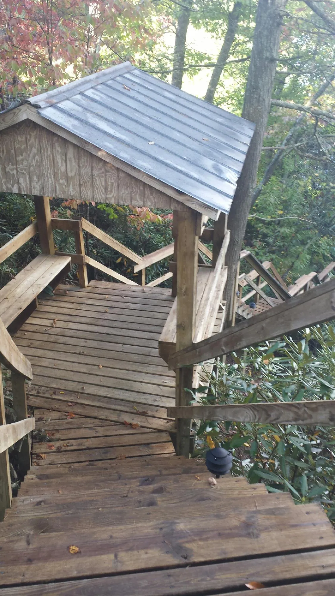 Metal roofed shelter over wooden steps on a wooded walkway — Skylight Repair & Installation work by our crew in Spirit Lake