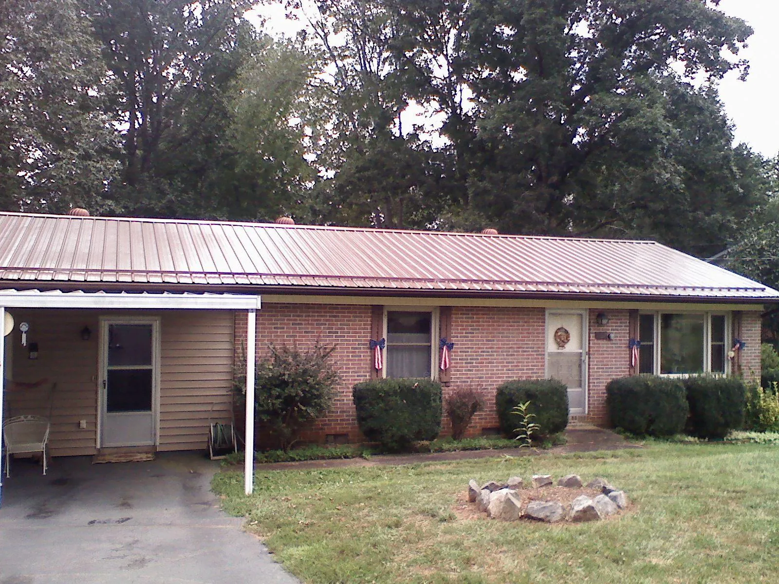 Bronze metal roof and carport on a brick ranch home — Roof Repair work by our crew in Spirit Lake